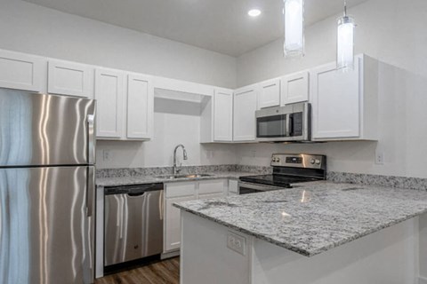 A kitchen with a granite countertop and stainless steel appliances.