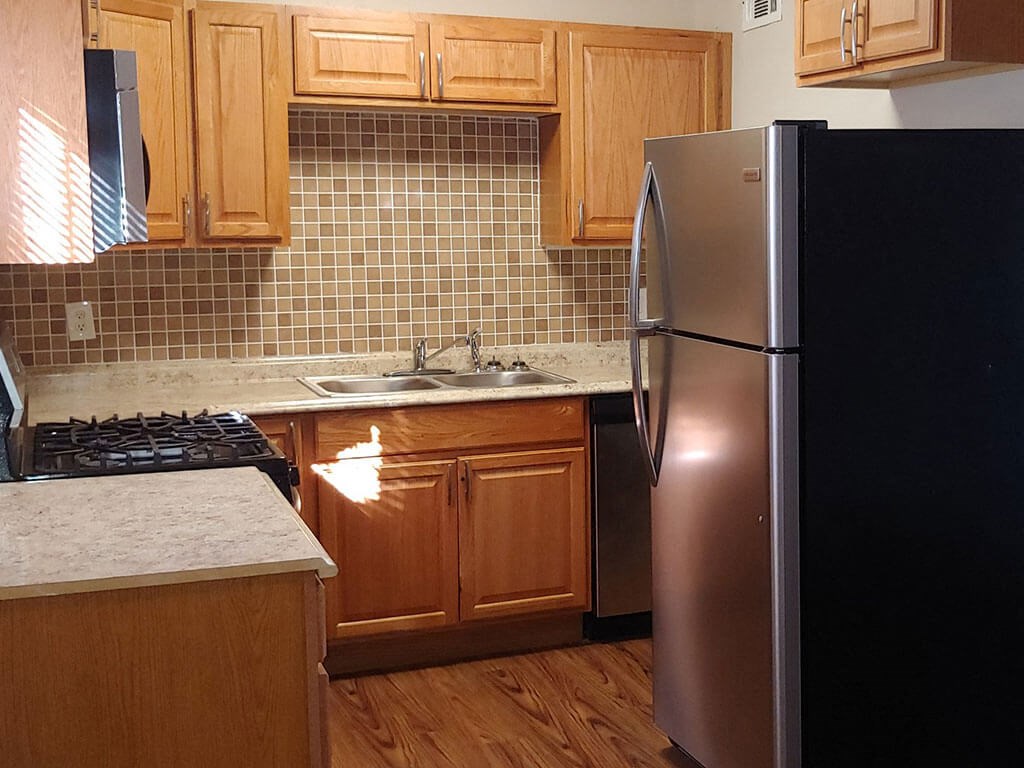a kitchen with wooden cabinets and a black refrigerator