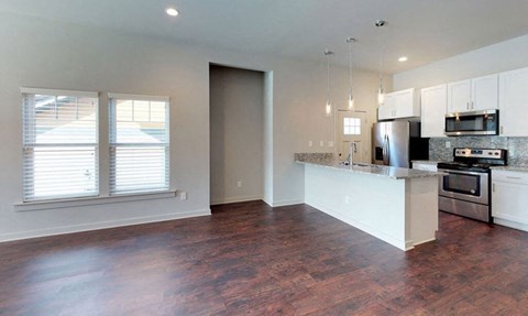 A kitchen with white cabinets and a wooden floor.