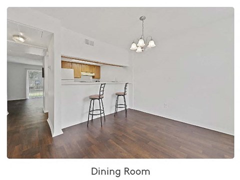 A dining room with a wooden floor and white walls.