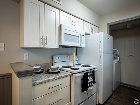 A kitchen with white appliances and cabinets.