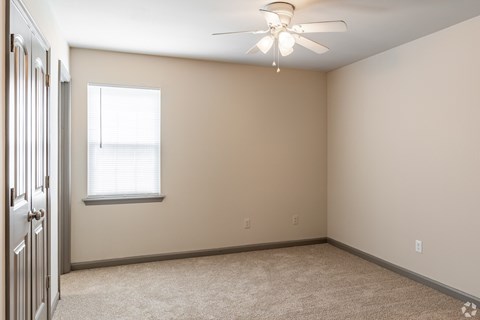 A room with a ceiling fan and a window.