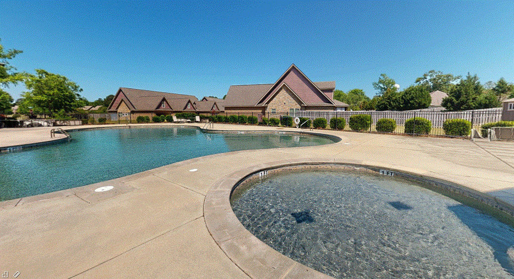 a swimming pool with a hot tub and a house in the background
