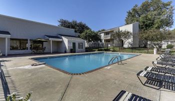 a swimming pool with chaise lounge chairs and a building in the background