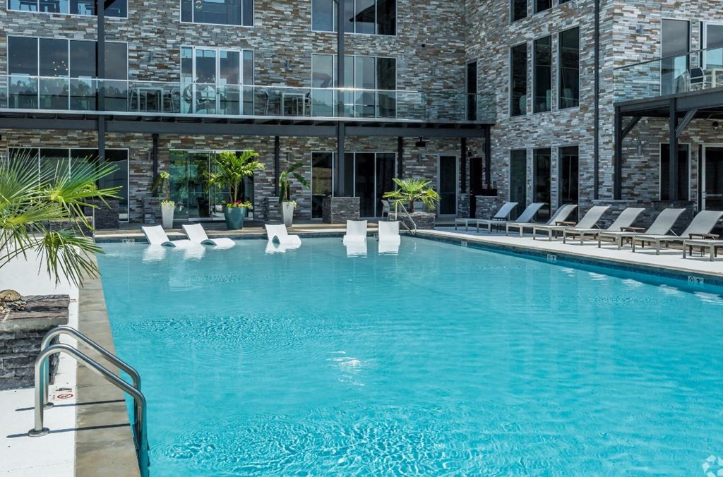 a large swimming pool with lounge chairs and a stone building in the background