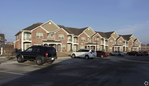 A black SUV is parked in front of a brick apartment building.