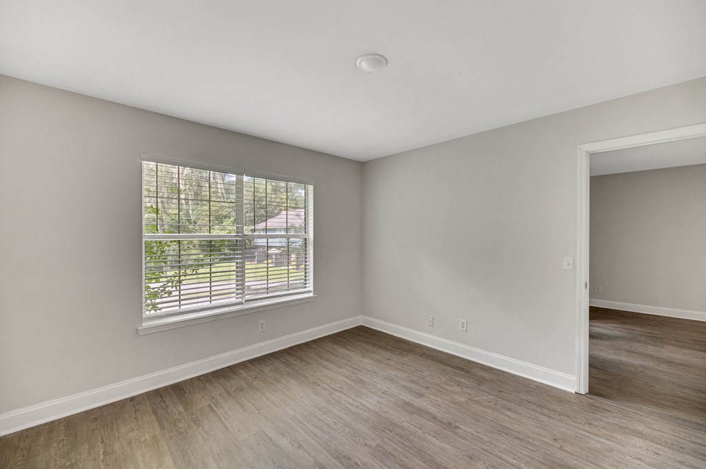 an empty living room with a large window and wood flooring