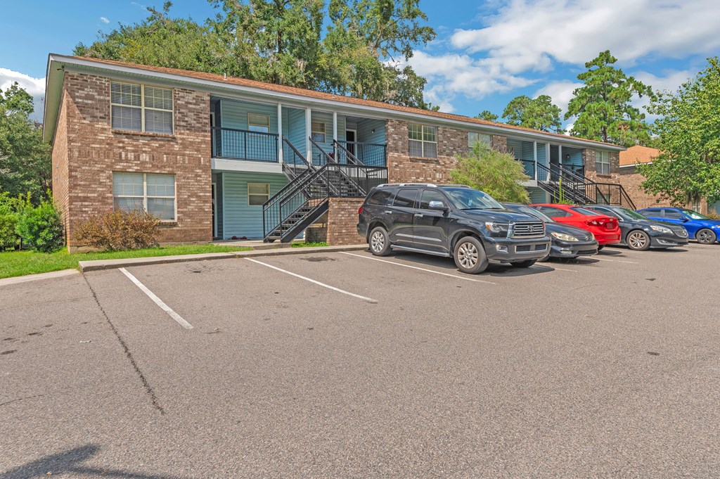 a parking lot in front of an apartment building with cars parked in front