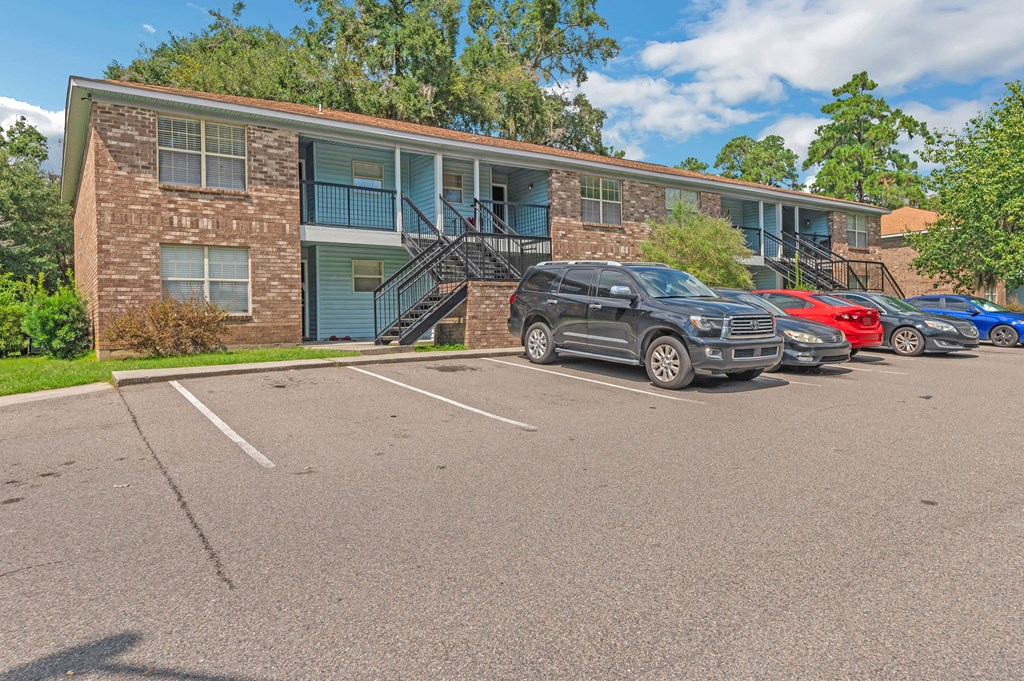 a parking lot in front of an apartment building with cars parked in front