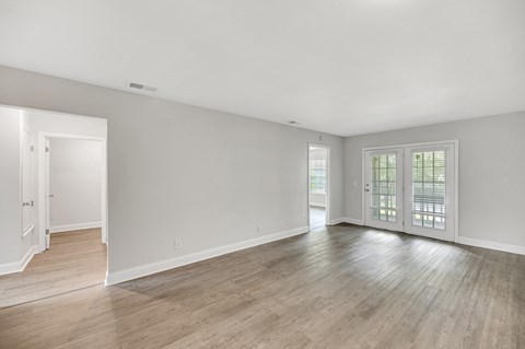 A spacious room with wooden flooring and white walls.