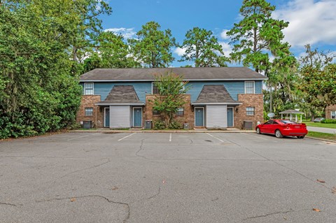 a red car parked in a parking lot in front of a house