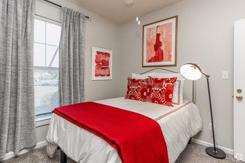 a bedroom with a red and white bed and a window