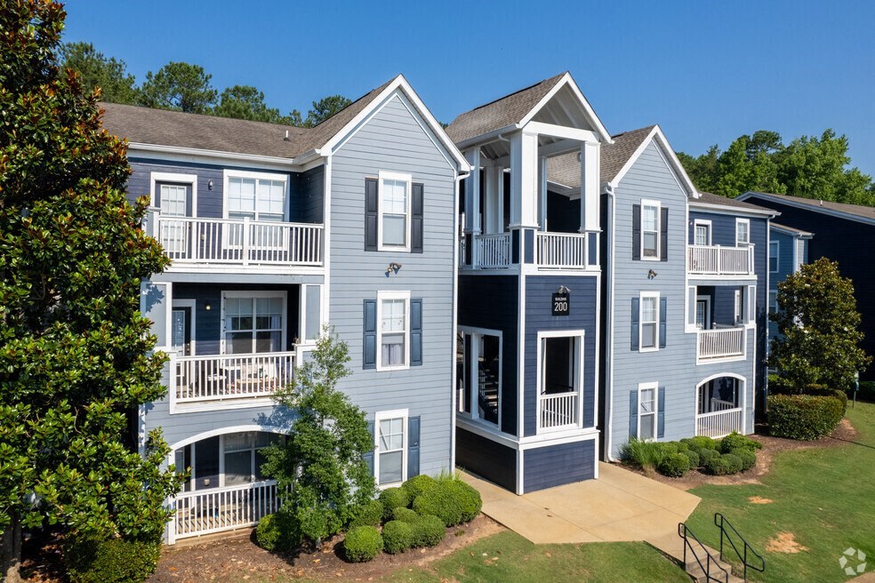 exterior view of three apartment buildings with balconies and a yard