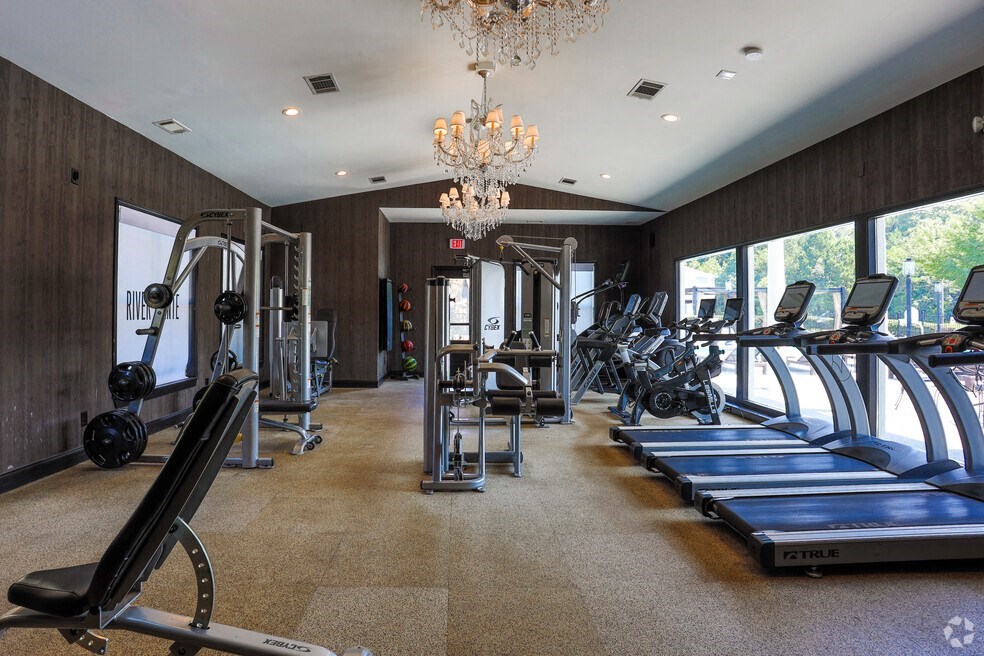 a gym with cardio equipment and a chandelier