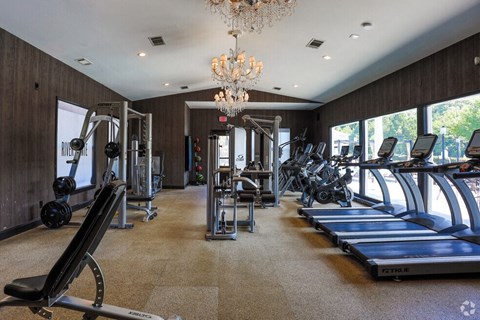 a gym with cardio equipment and a chandelier