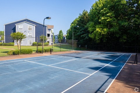 a blue tennis court with a building in the background