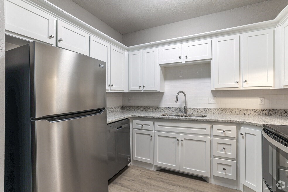 a kitchen with white cabinets and a stainless steel refrigerator