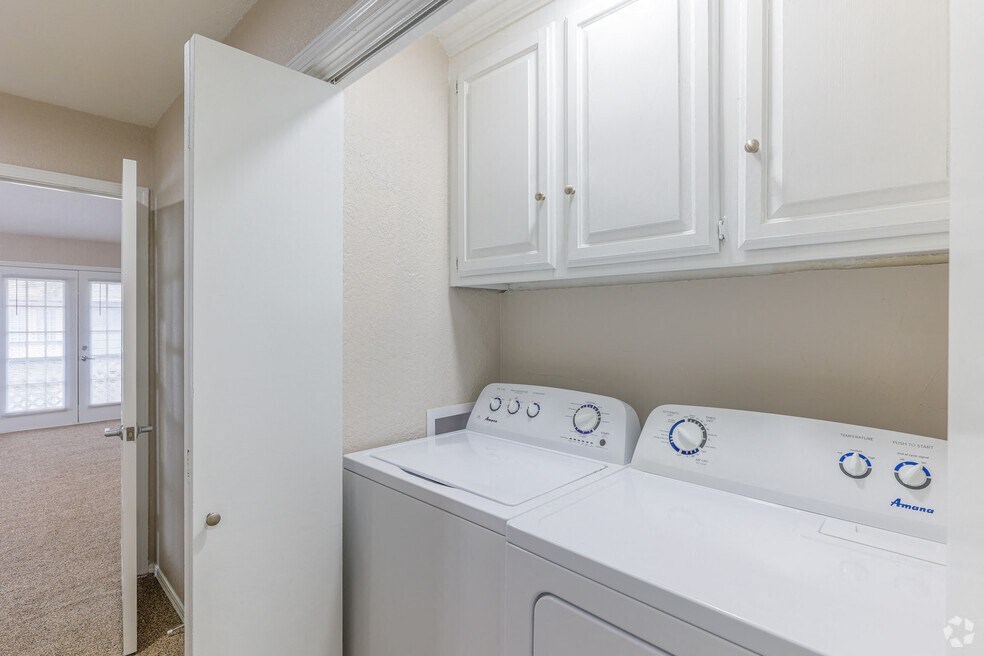 a white washer and dryer in a laundry room with white cabinets