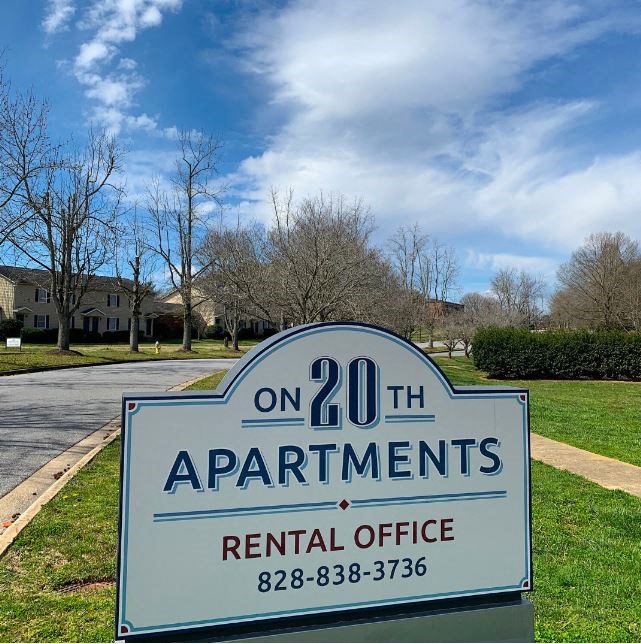 a sign in a grassy area with houses in the background