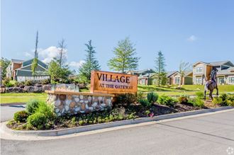 a sign that says village at the gateway with houses in the background