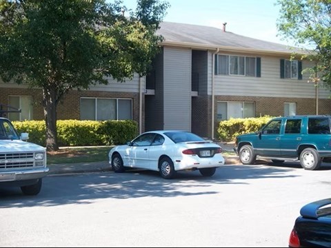 A white car is parked on the side of the road in front of a building.