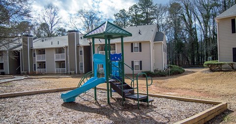 A playground with a blue slide and a green roofed structure.