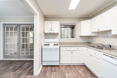 a kitchen with white cabinets and a stove and a glass door