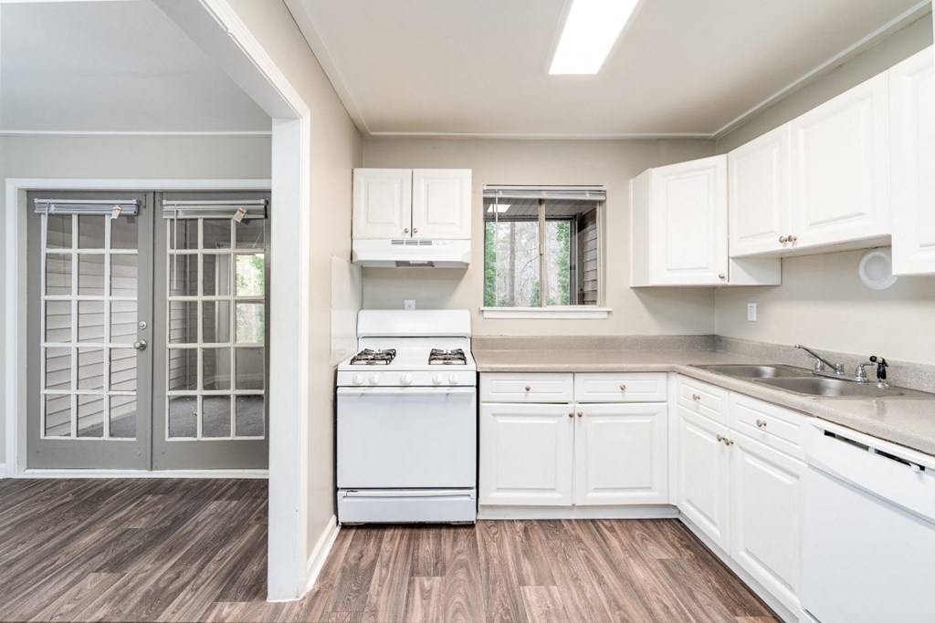 a kitchen with white cabinets and a stove and a glass door