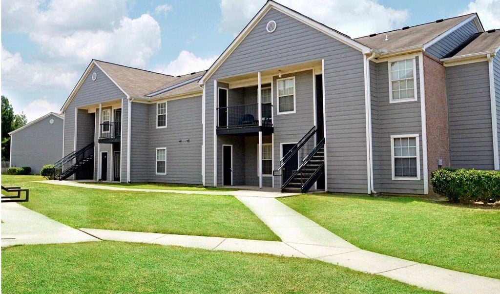 an apartment building with gray siding and a sidewalk
