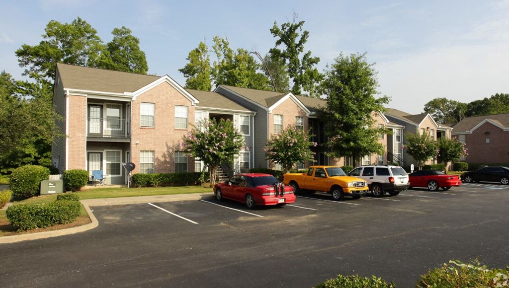 a parking lot with cars parked in front of apartment buildings