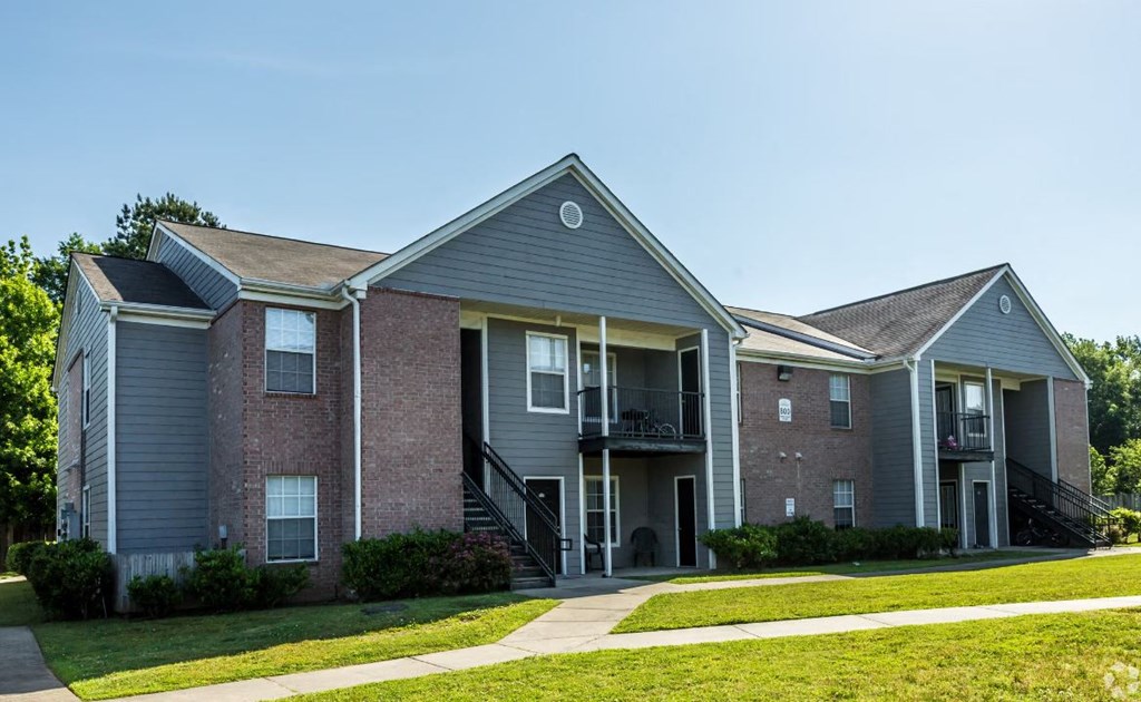 an apartment building with a lawn and a sidewalk
