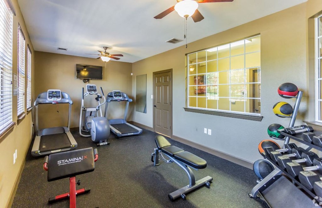 a gym with exercise machines and weights at the retreat at thousand oaks apartments
