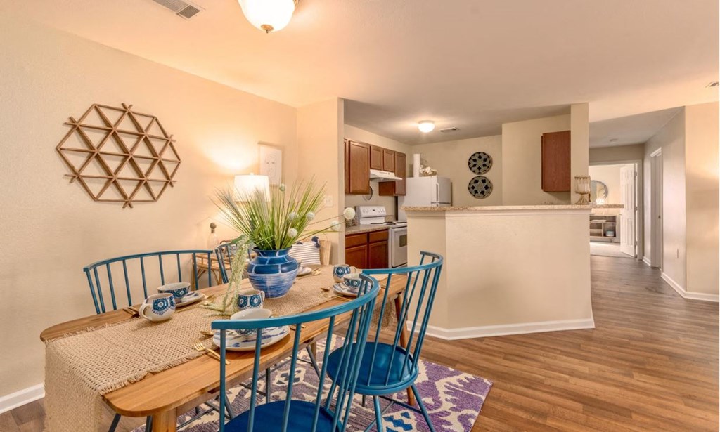 a dining room table with blue chairs next to a kitchen