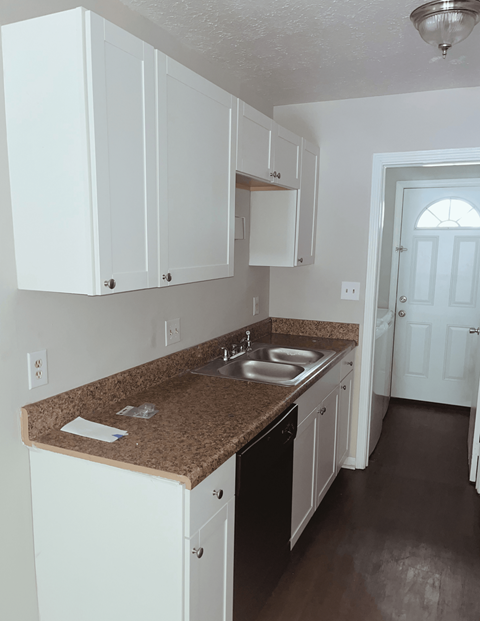 A kitchen with brown granite countertops and white cabinets.