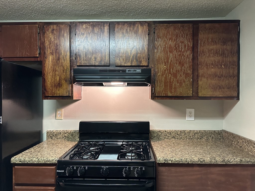 a kitchen with a stove and a counter top with wooden cabinets
