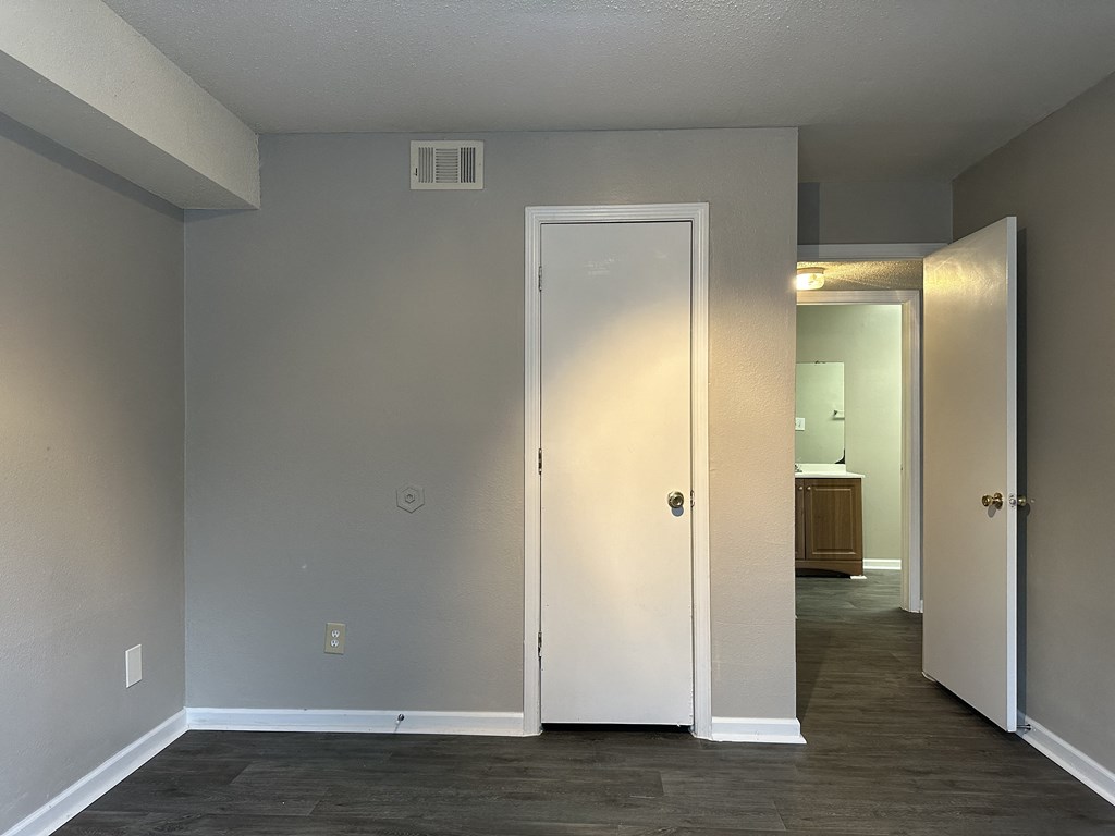 an empty living room with a hallway to a closet and a door to a bathroom