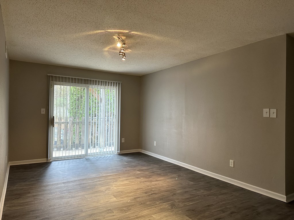an empty living room with wood floors and a sliding glass door