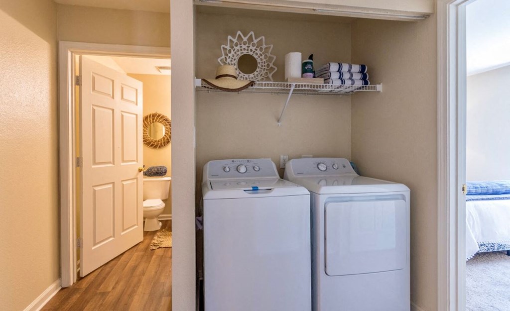 a closet with two washer and dryers and a door to a bathroom