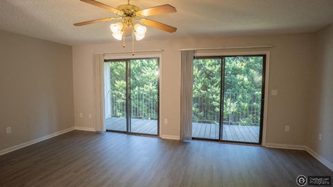 an empty living room with sliding glass doors and a ceiling fan
