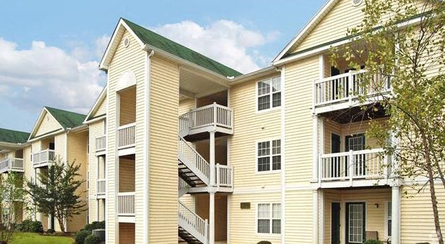 a yellow apartment building with balconies and trees