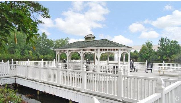a white pier with a gazebo and a white fence