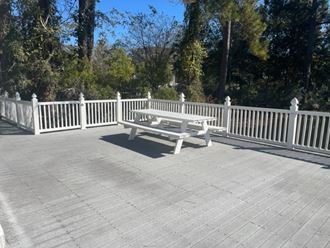 a white bench sitting on a deck next to a fence