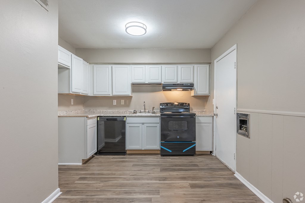 an empty kitchen with white cabinets and a black stove and oven