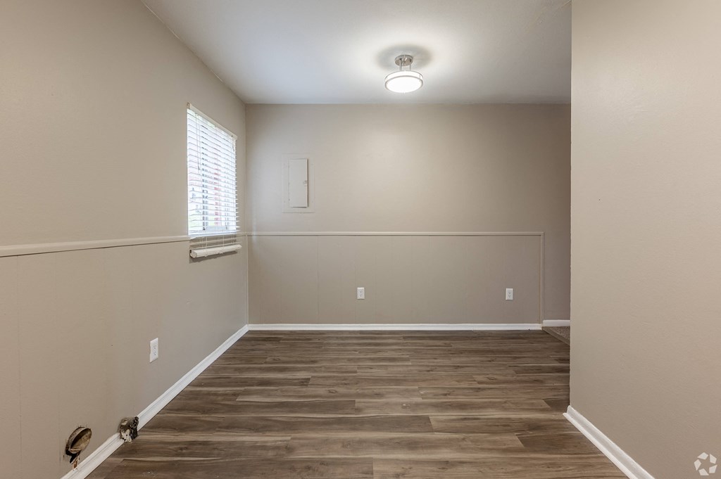 an empty living room with wood flooring and a window