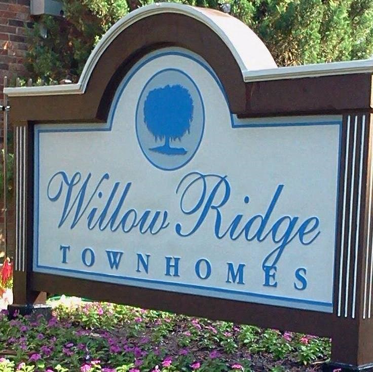 a sign for willow ridge townhomes in front of a garden