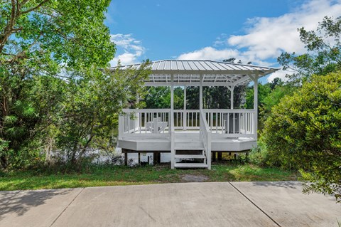 a white gazebo with a white bench next to a sidewalk