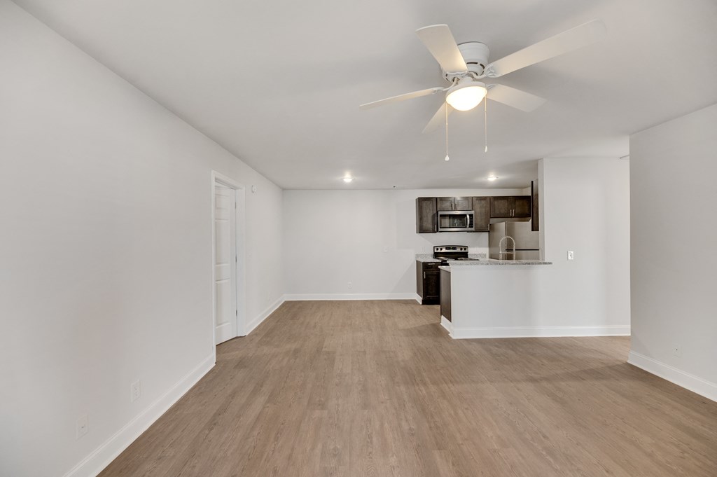 an empty living room and kitchen with a ceiling fan