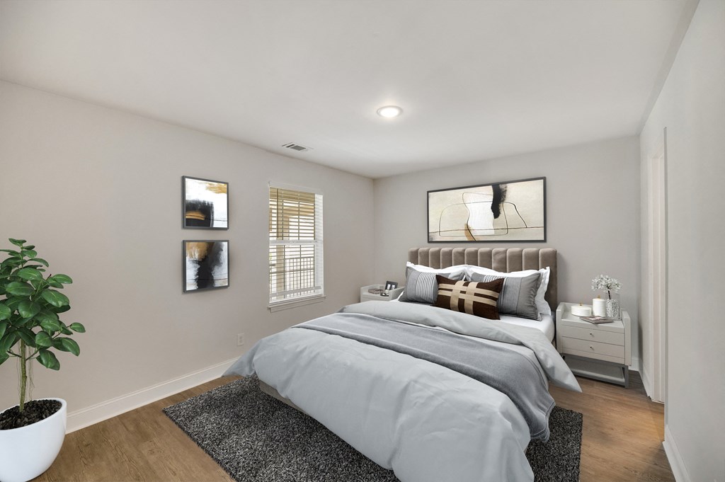a bedroom with white walls and a bed with grey blankets and pillows