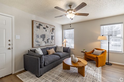 A living room with a grey couch, a coffee table, and a painting on the wall.