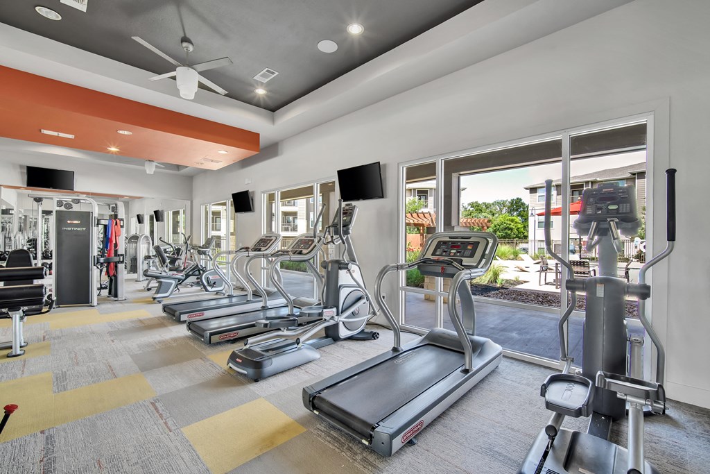 a gym with treadmills and other exercise equipment and windows